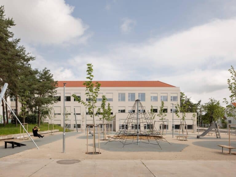 Exterior view of the new school pavilion extension showing the playground and modern facade with large windows.