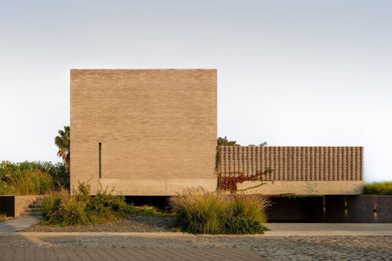 Exterior view of Capuchinas House in Queretaro featuring a monolithic concrete block facade and a geometric screen wall.