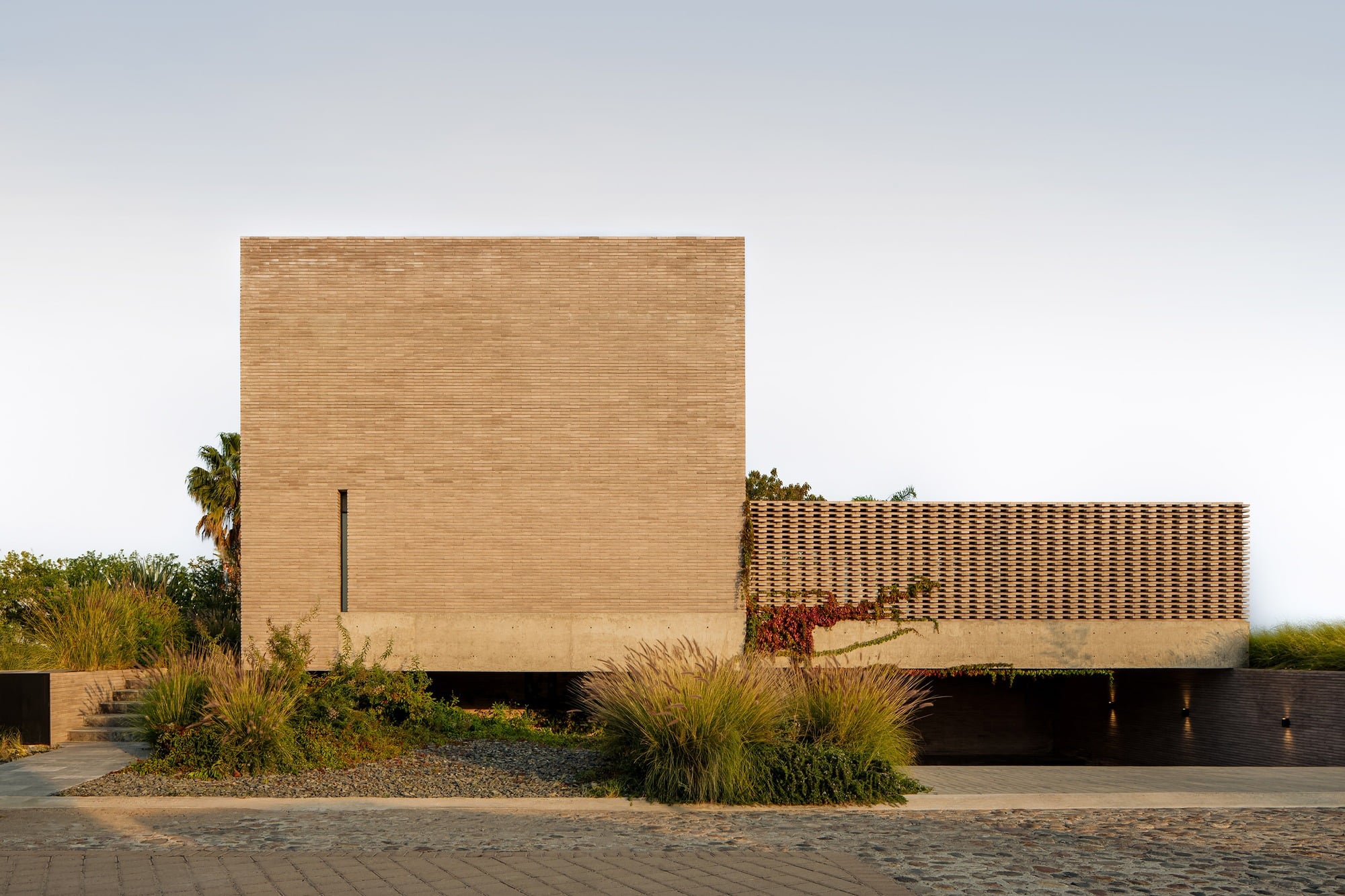 Exterior view of Capuchinas House in Queretaro featuring a monolithic concrete block facade and a geometric screen wall.
