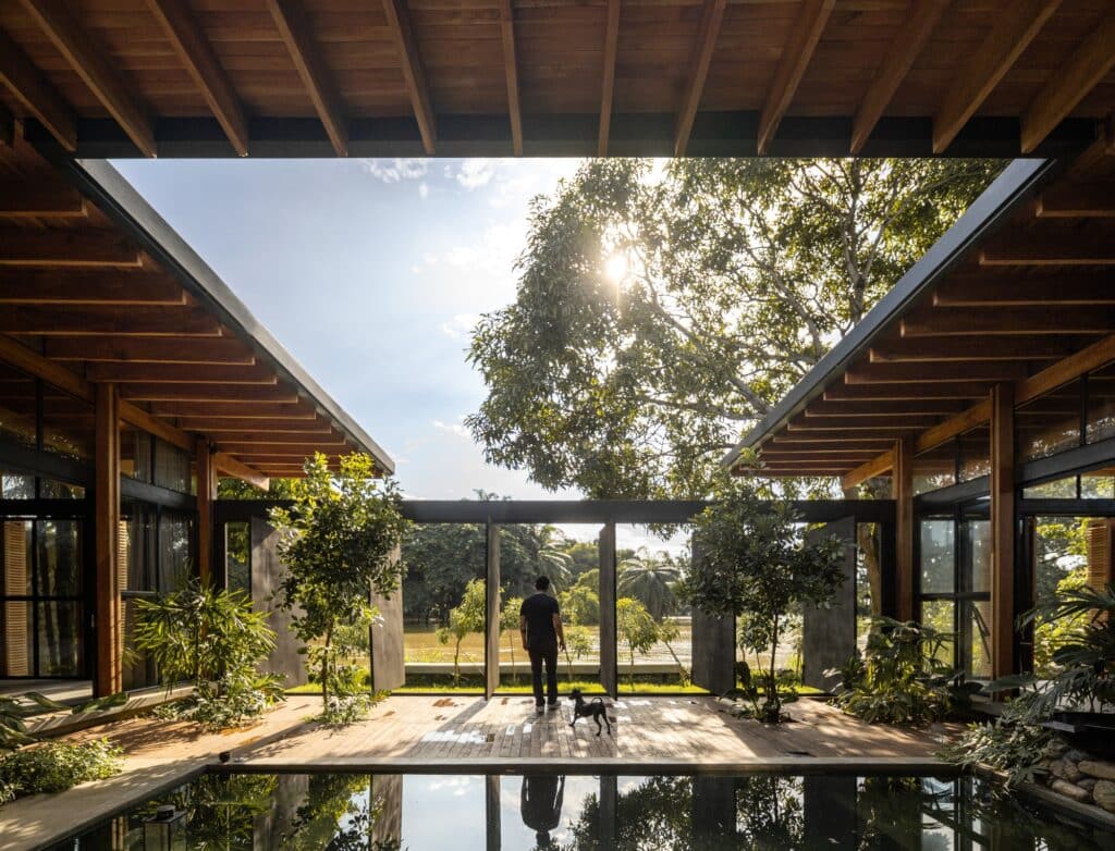 Internal courtyard of La Casa del Tiempo featuring a central water mirror, wooden structure, and a view towards the Babahoyo River.