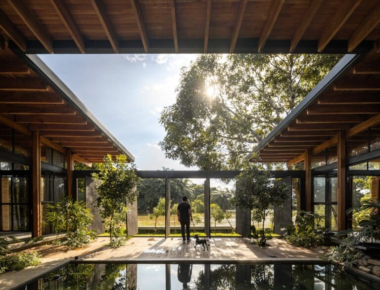 Internal courtyard of La Casa del Tiempo featuring a central water mirror, wooden structure, and a view towards the Babahoyo River.