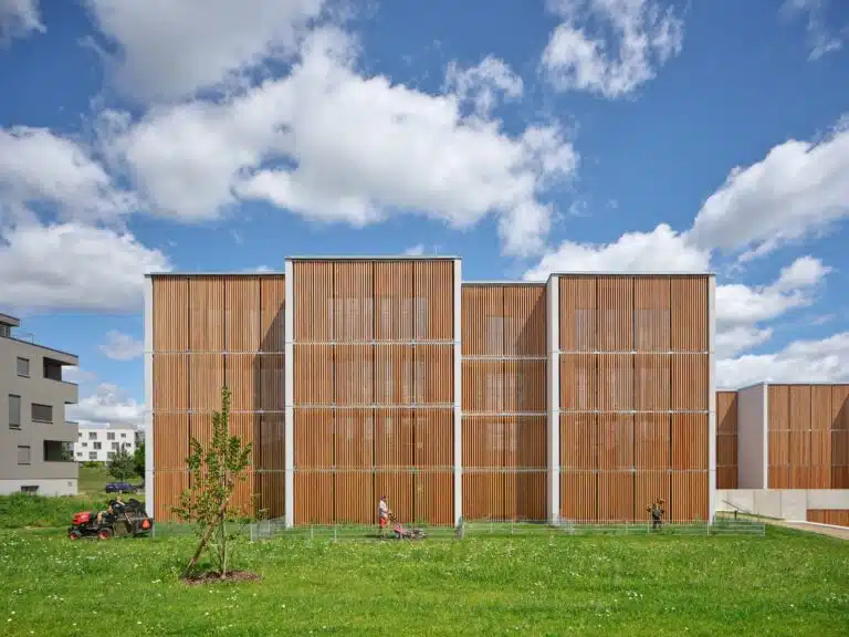 Front view of Klafar wooden housing facade with vertical wooden slats and green lawn in Zdar nad Sazavou.