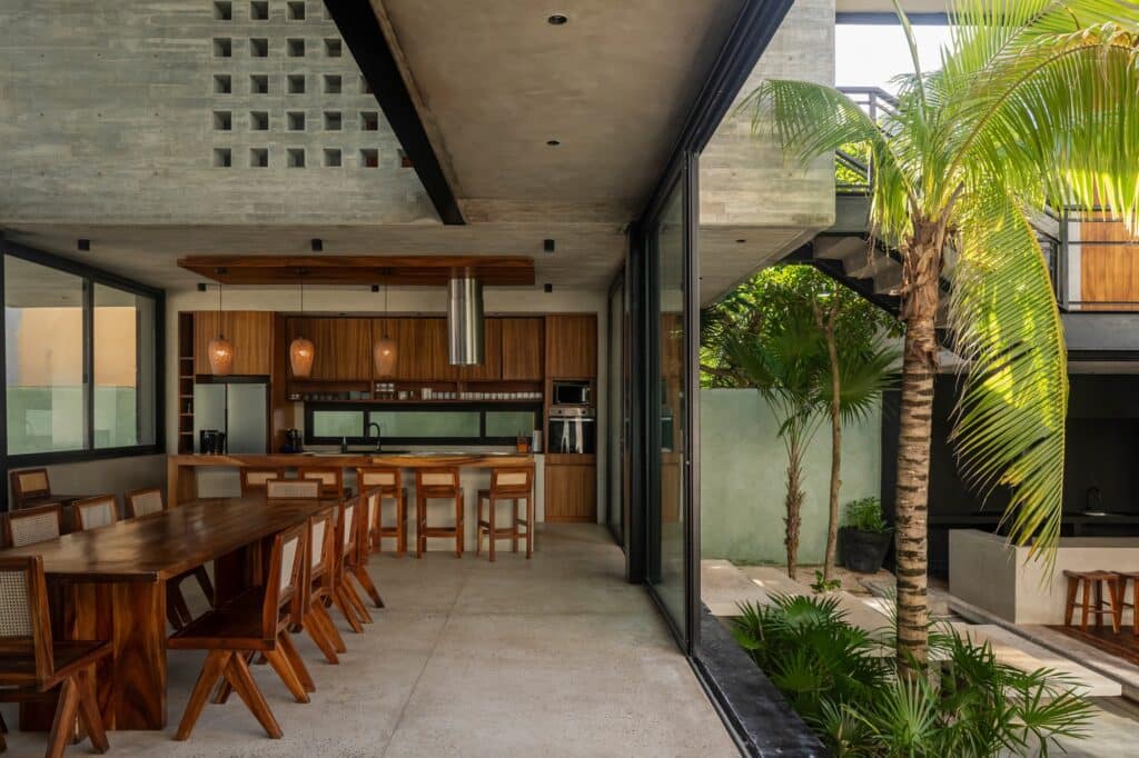 Open-plan kitchen and dining area at Vihara House featuring wooden furniture and seamless indoor-outdoor transition.