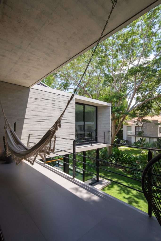View from the upper floor balcony of Casa Refugio with a hammock, looking over the garden and surrounding trees.