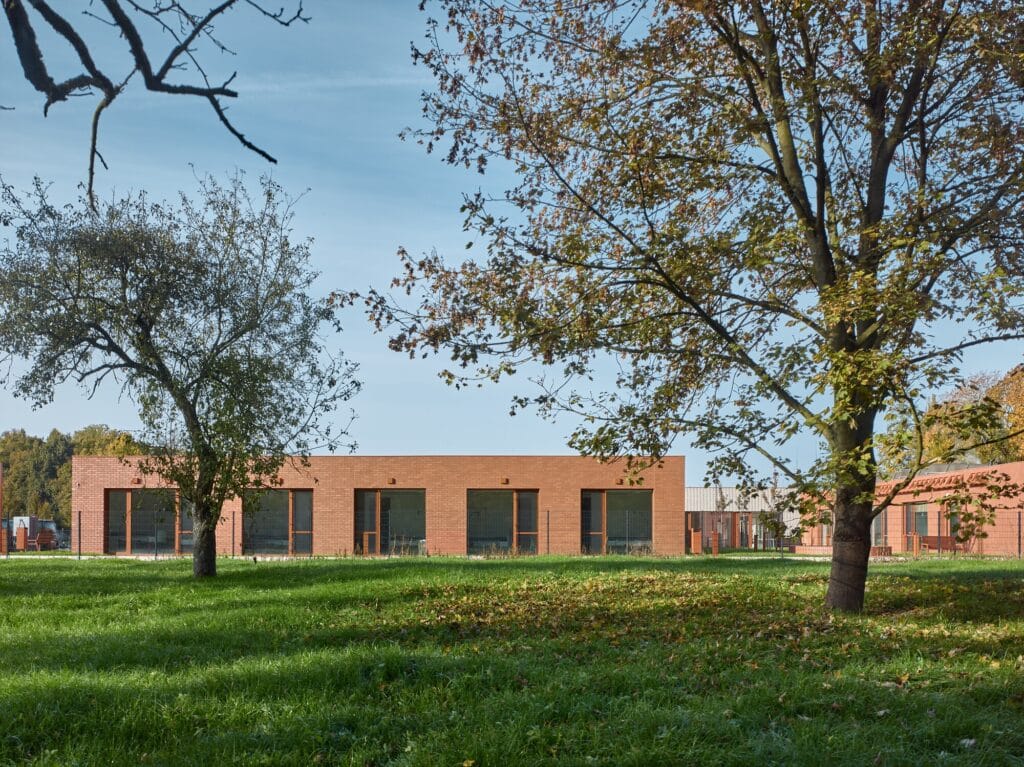 Brick facade of the senior home viewed through trees in a former orchard setting.