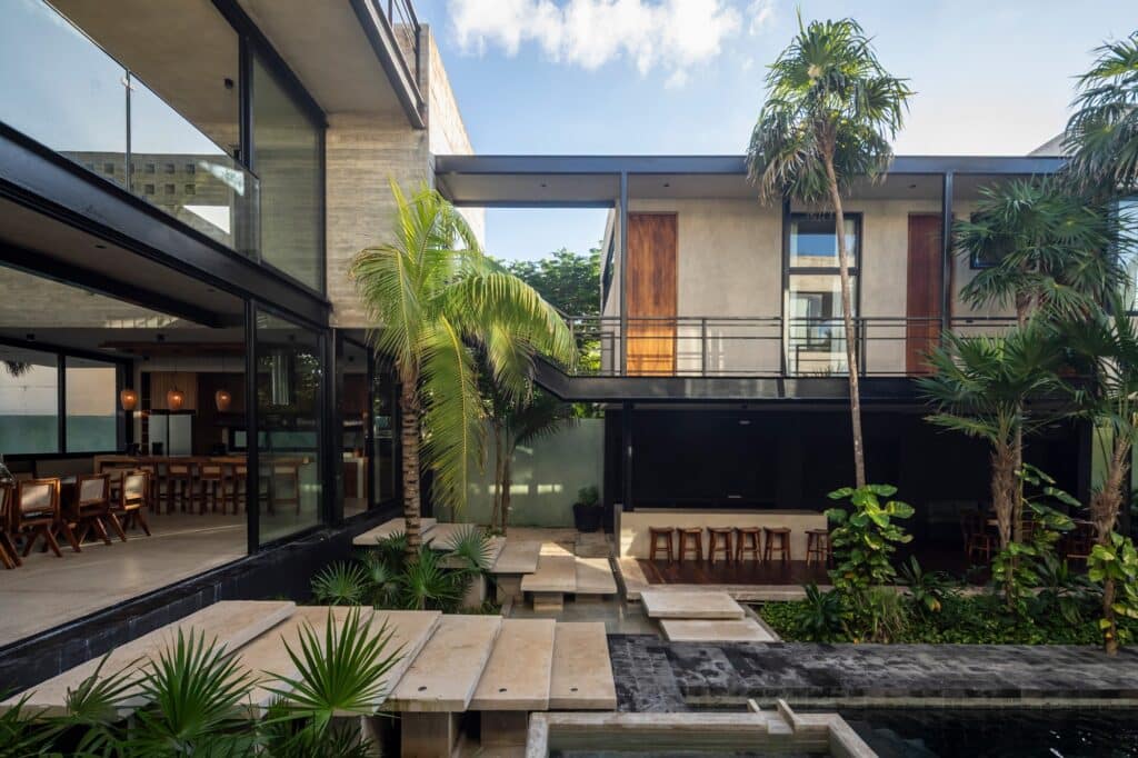 Modern residential courtyard with floating concrete steps, a reflecting pool, and a steel bridge connecting upper levels.