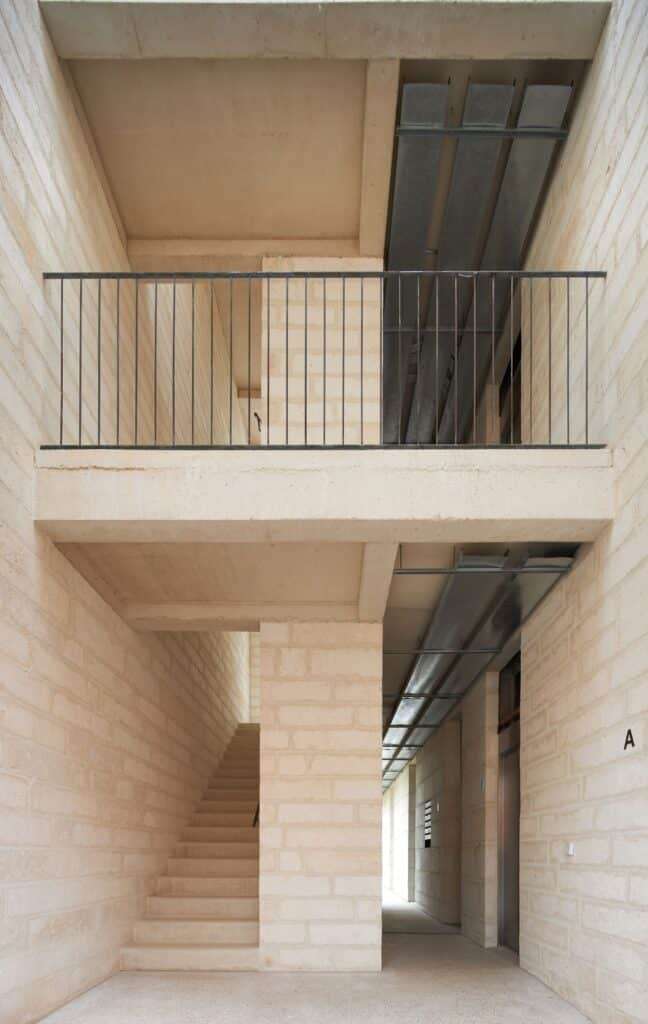 Vertical circulation area of the building showing a concrete staircase, Mares stone block walls, and exposed ceiling conduits.