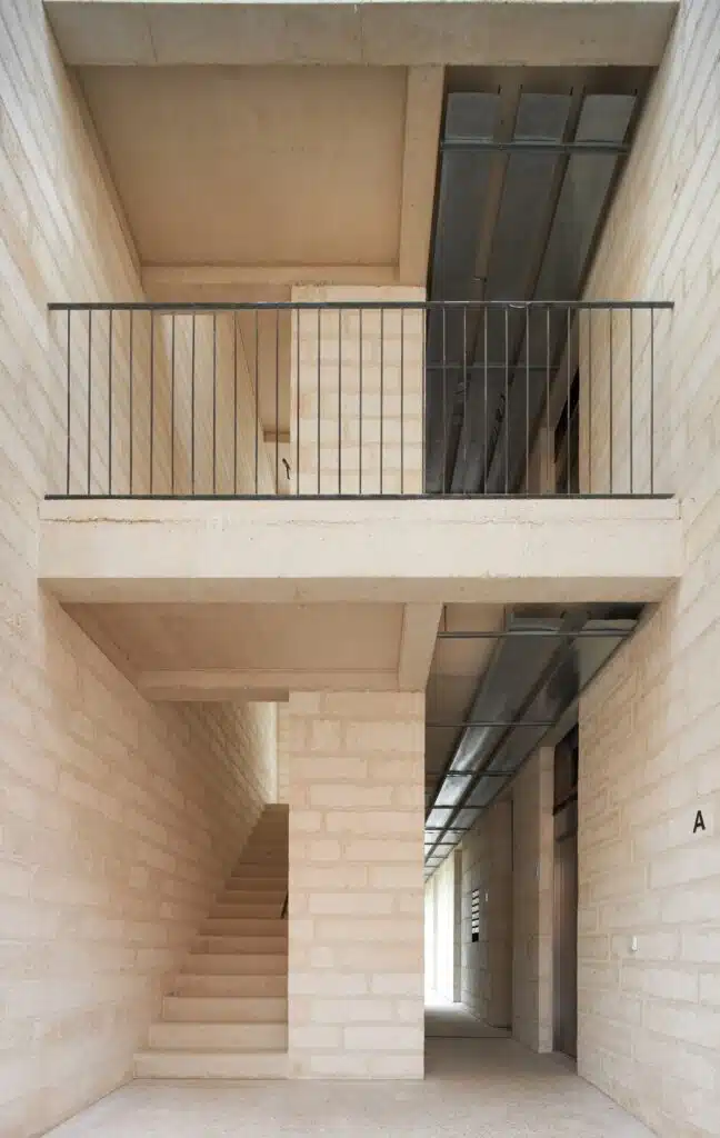 Vertical circulation area of the building showing a concrete staircase, Mares stone block walls, and exposed ceiling conduits.