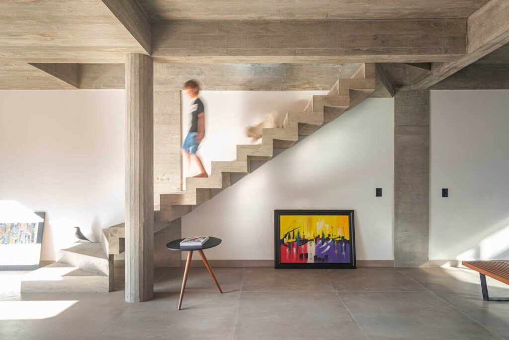 Minimalist linear concrete staircase against a white wall with natural sunlight shadows.