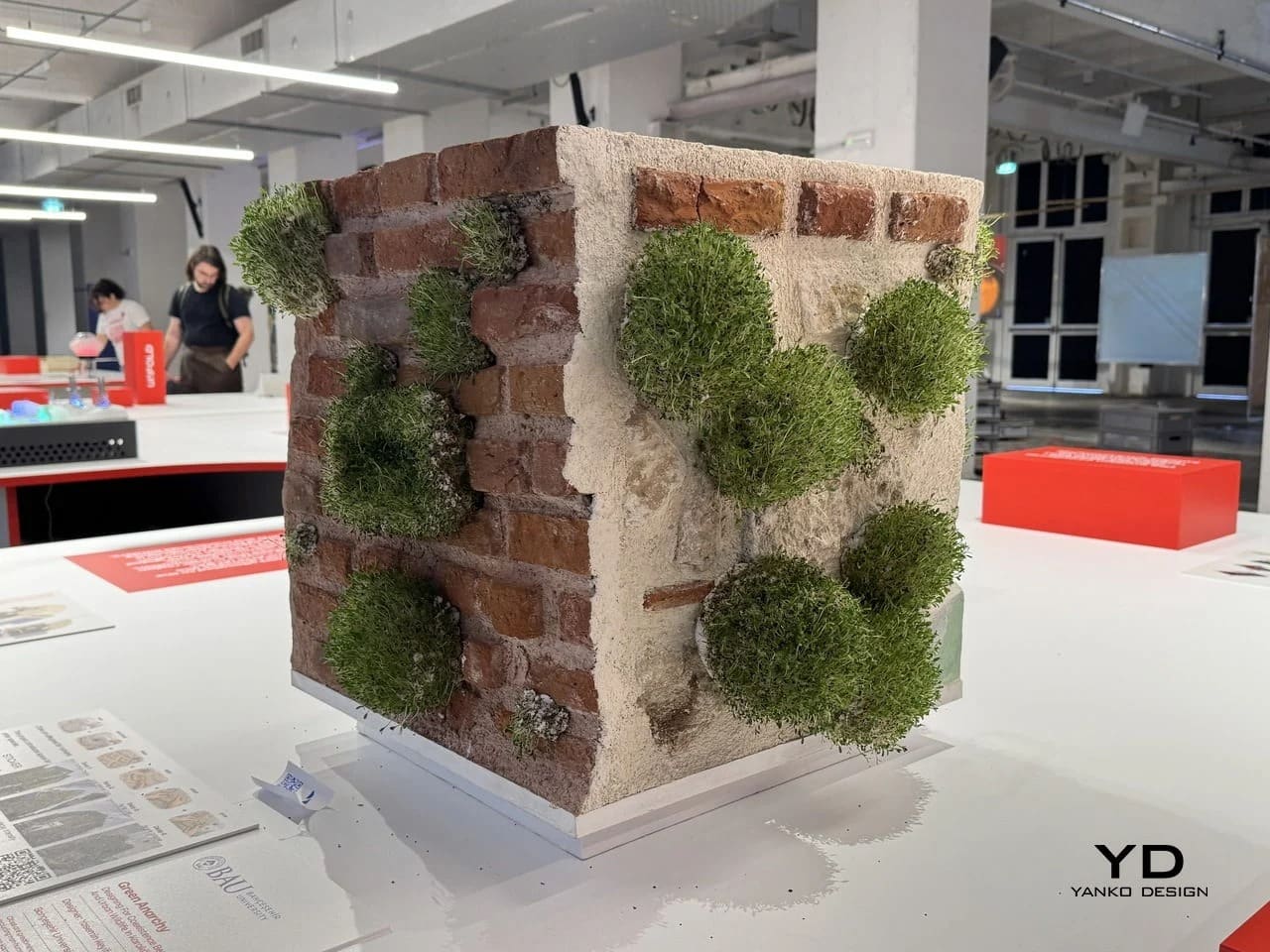 Eye-level view of the Green Anarchy wall model showing brick and plaster sides with moss-like growth.