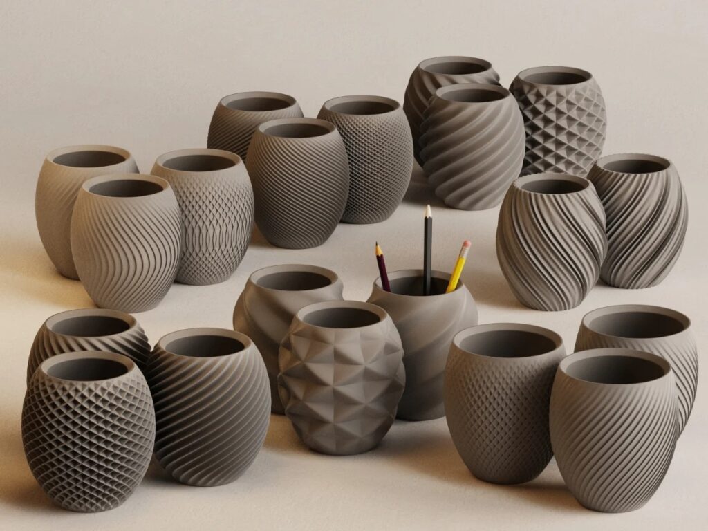A wide collection of 3D printed grey desk organizers from the Aya and Sfera series featuring various parametric patterns like spiral, wavy, and pinecone textures.