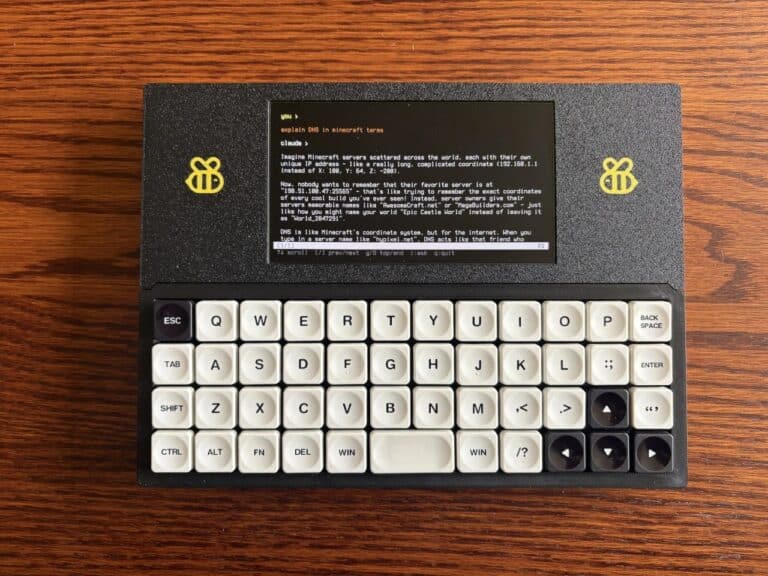 Top view of the Bee Write Back writerdeck device displaying a text-based interface on an AMOLED screen with a mechanical keyboard on a wooden surface.