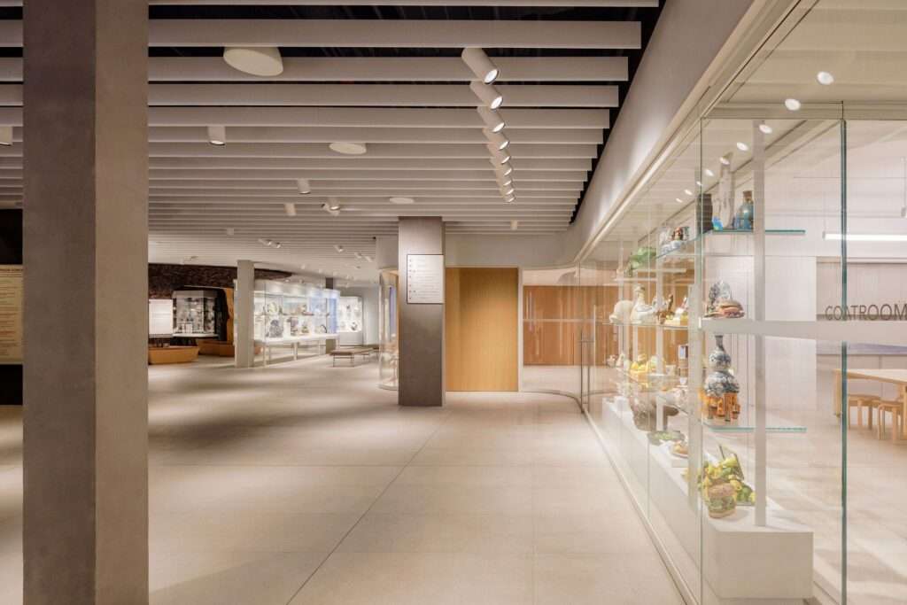 Wide view of the Gardiner Museum corridor showing integrated glass display cases and community learning spaces.
