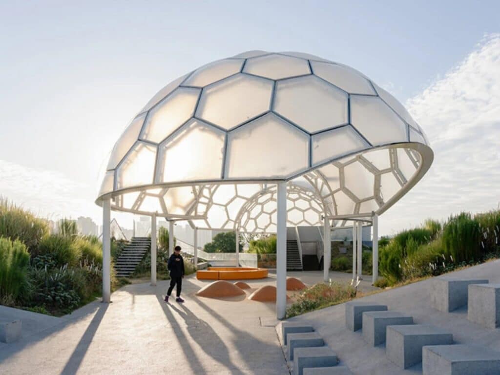Close-up of a translucent hexagonal canopy structure on the rooftop of Yongping Warehouse with modern concrete seating and greenery.