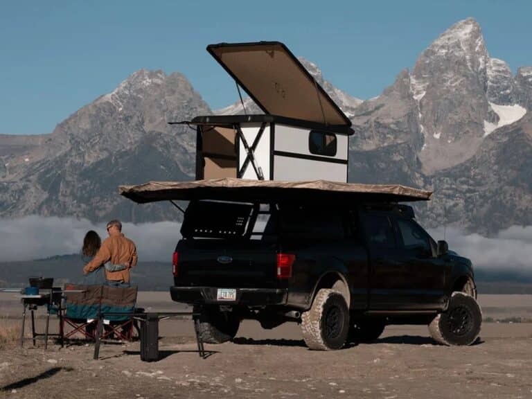 Altus hardwall rooftop cabin deployed on a black pickup truck in a mountainous landscape with a side awning extended.
