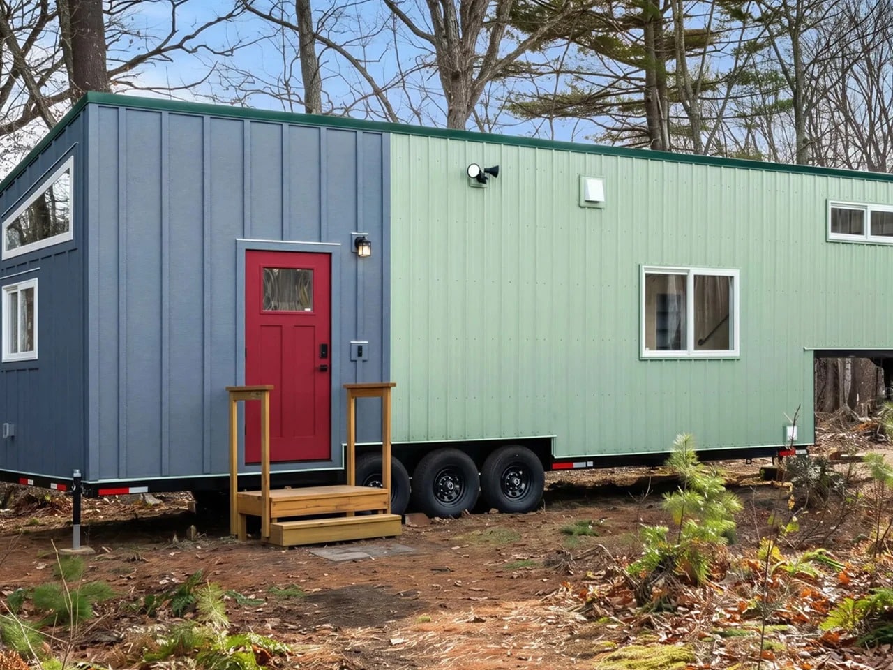 Exterior view of The Knoll tiny home built on a triple-axle gooseneck trailer featuring blue and sage green board and batten siding.