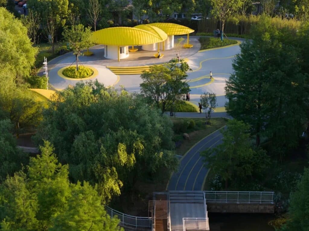 Aerial perspective of Orchestra Park showing the transition from dense green trees to modern yellow architectural structures near the waterfront.