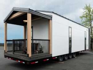 Exterior view of the Urban Gable Park tiny home showing its white facade and covered wooden porch.