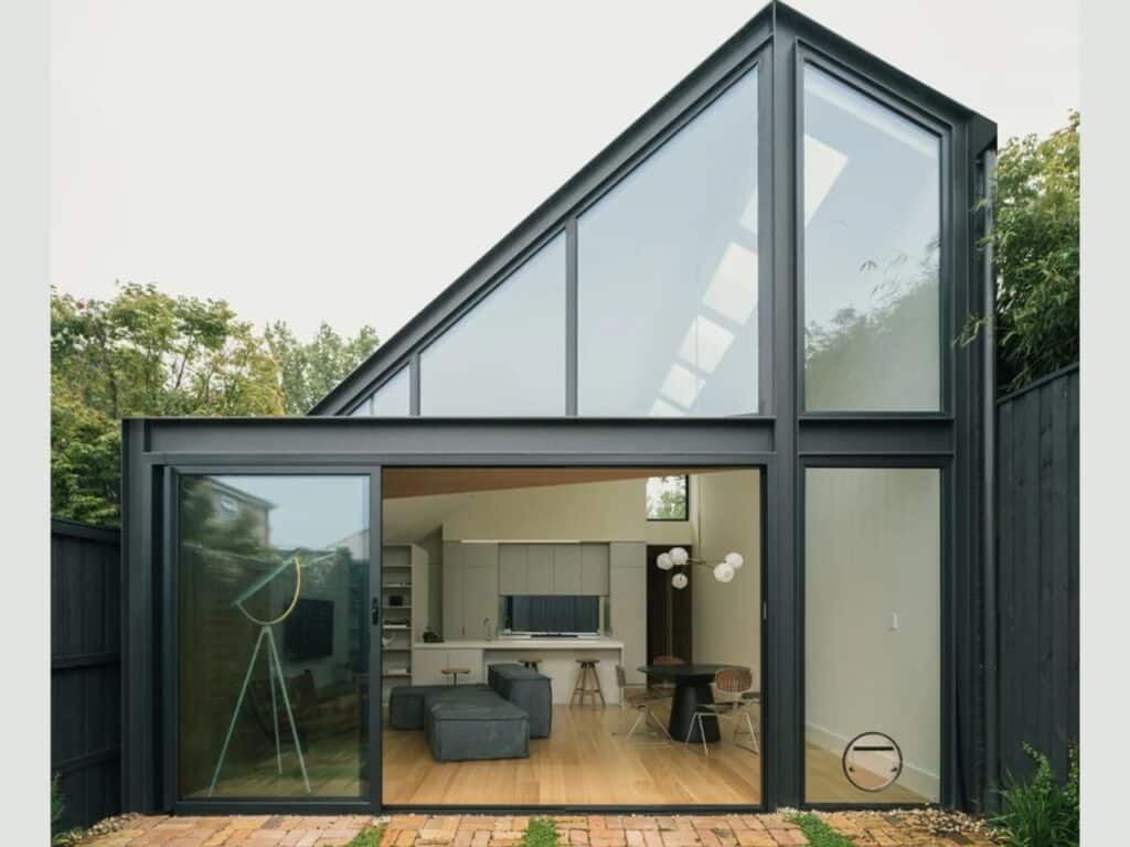 Modern rear extension of Abbie Abbotsford Terrace featuring a sharp-angled roof and large sliding glass doors opening to a brick courtyard.