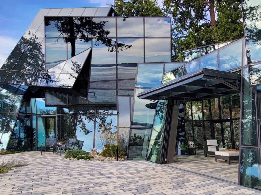 Exterior crystalline glass facade of F-House with irregular angular panels reflecting trees and sky.