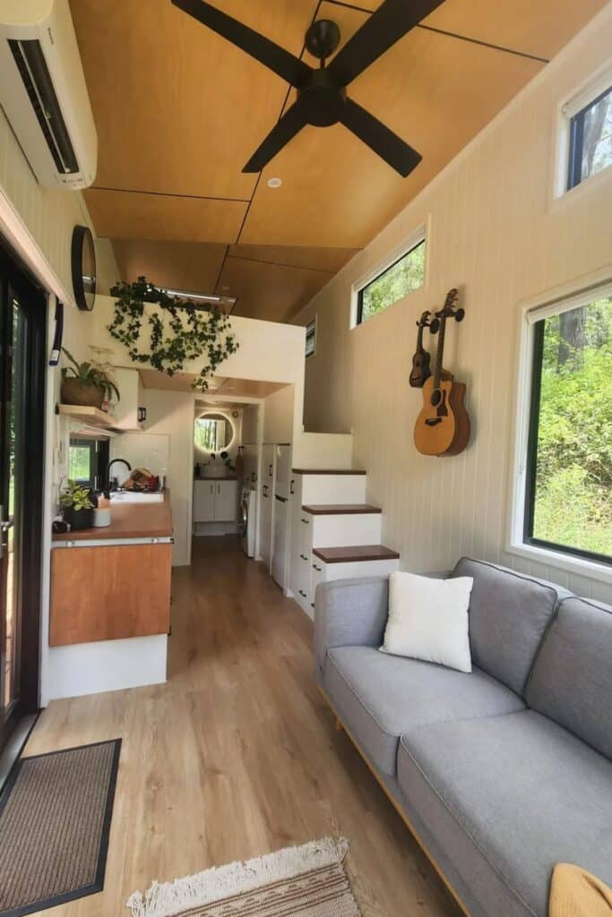 Interior view of the Currumbin tiny house showing the kitchen, living area, and stairs with built-in storage.