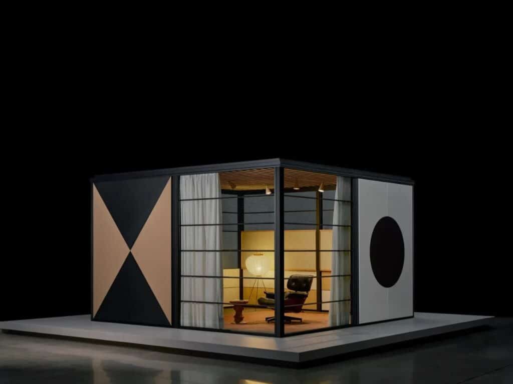 Small modular Eames Pavilion unit with geometric black and tan panels and a classic Eames Lounge Chair inside.