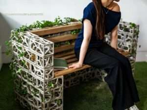 A person sitting on the PhytoSymbiosis bio-concrete and wood interactive bench, experiencing the integration of design and nature.