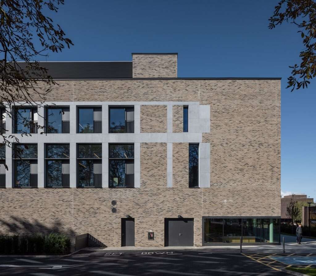 Detail of the brick and limestone facade of the University of Limerick Student Centre under a clear blue sky.