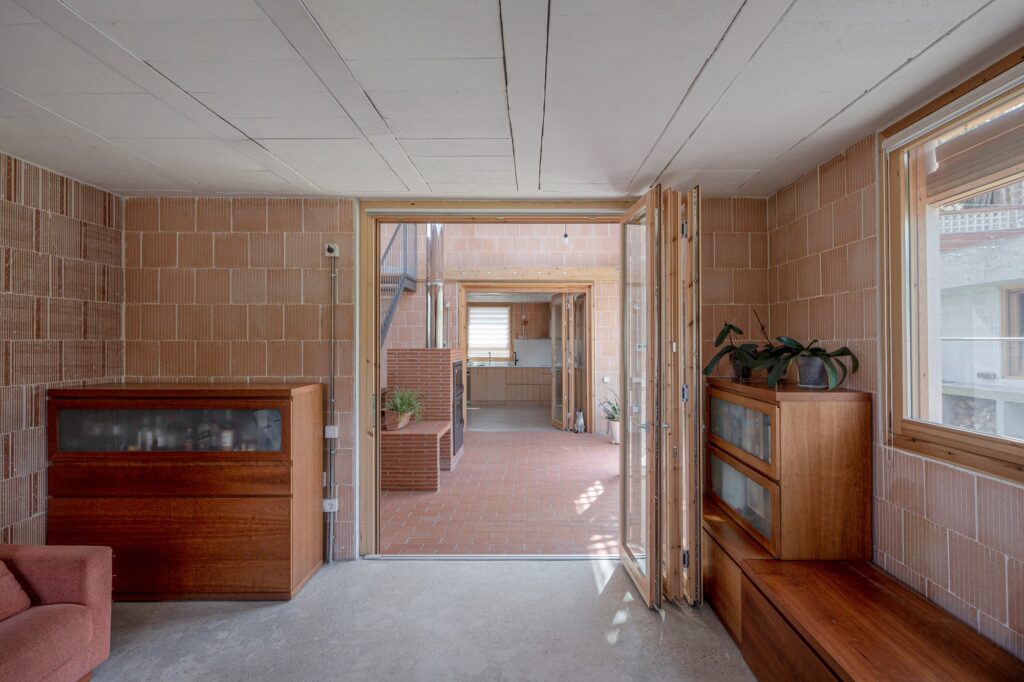 View from a living area looking through glass folding doors toward a central brick-paved courtyard and the kitchen.