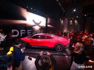 Side view of a sleek red futuristic concept car displayed at the Dreame Next event inside the Palace of Fine Arts, San Francisco.