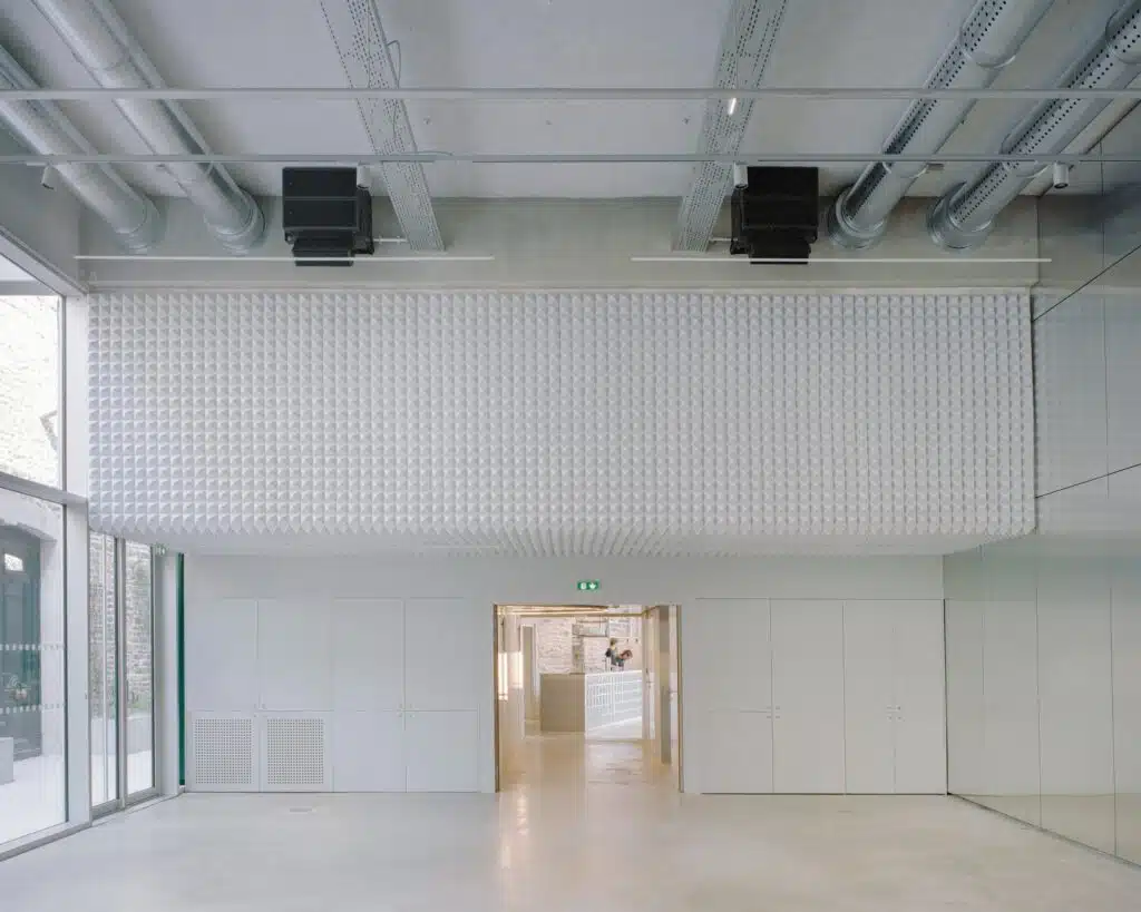 Interior view of a white acoustic textured wall above a clean minimalist workspace in the renovated industrial complex.