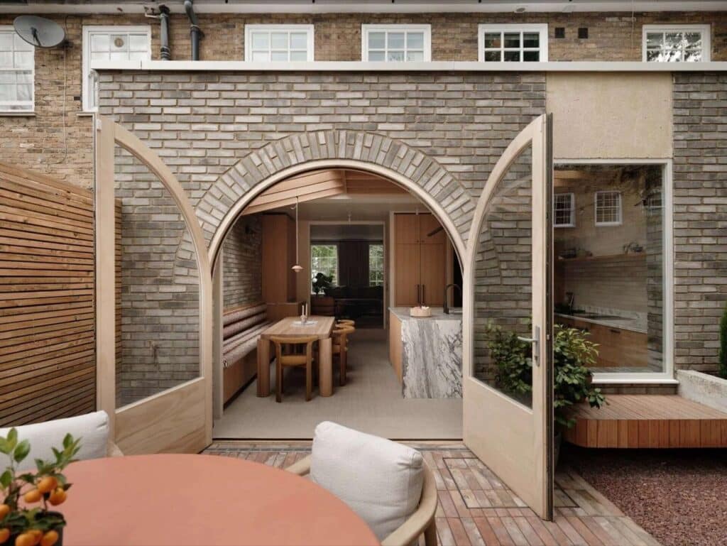 Arched brick extension of House 65A in Islington featuring large wooden-framed glass doors opening to a garden.