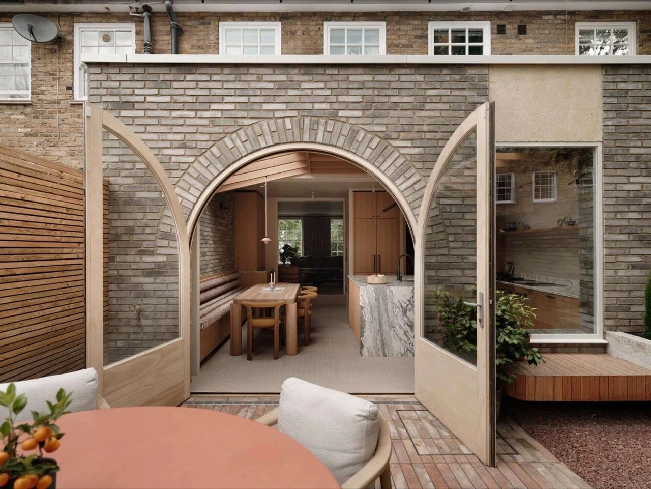 Arched brick extension of House 65A in Islington featuring large wooden-framed glass doors opening to a garden.