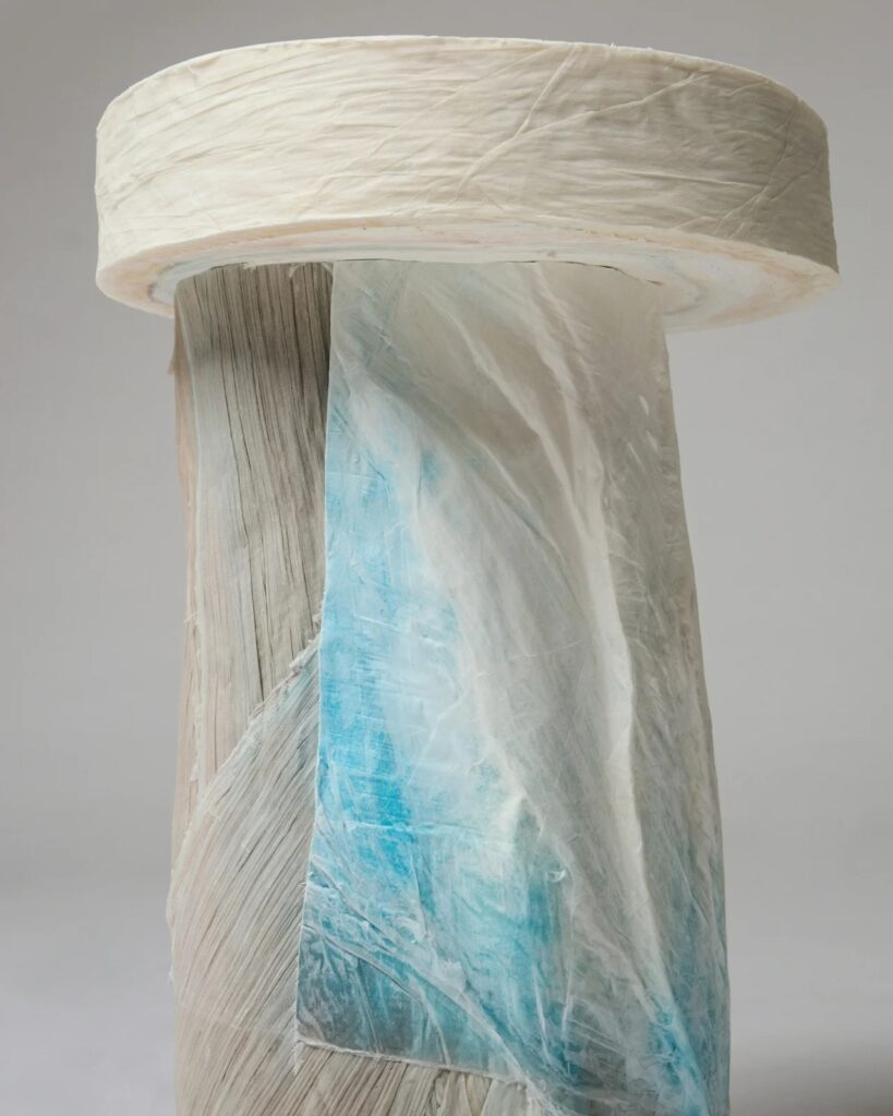Close-up of a paper log pillar with translucent blue dye and visible fiber textures.