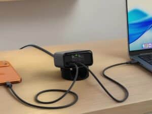 Satechi ChargeView 140W GaN charger on a wooden desk charging a laptop and iPhone, showing real-time power distribution on its digital display.