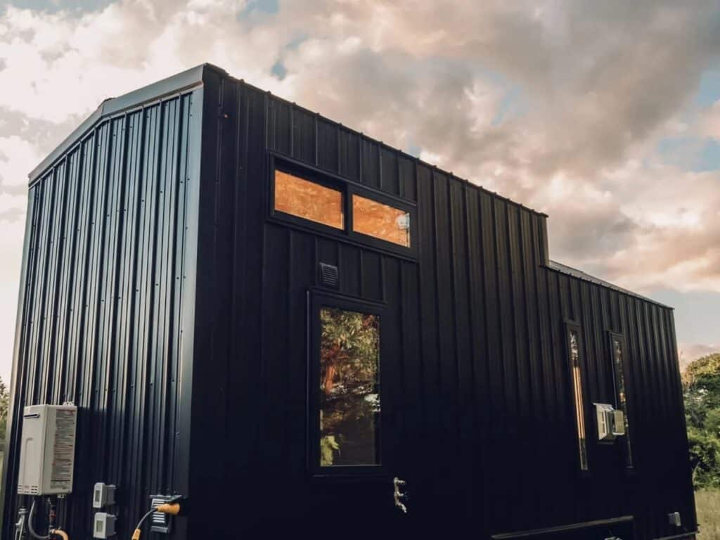 Architectural detail of the Scandi Inn's vertical black metal cladding and window placement against a cloudy sky.