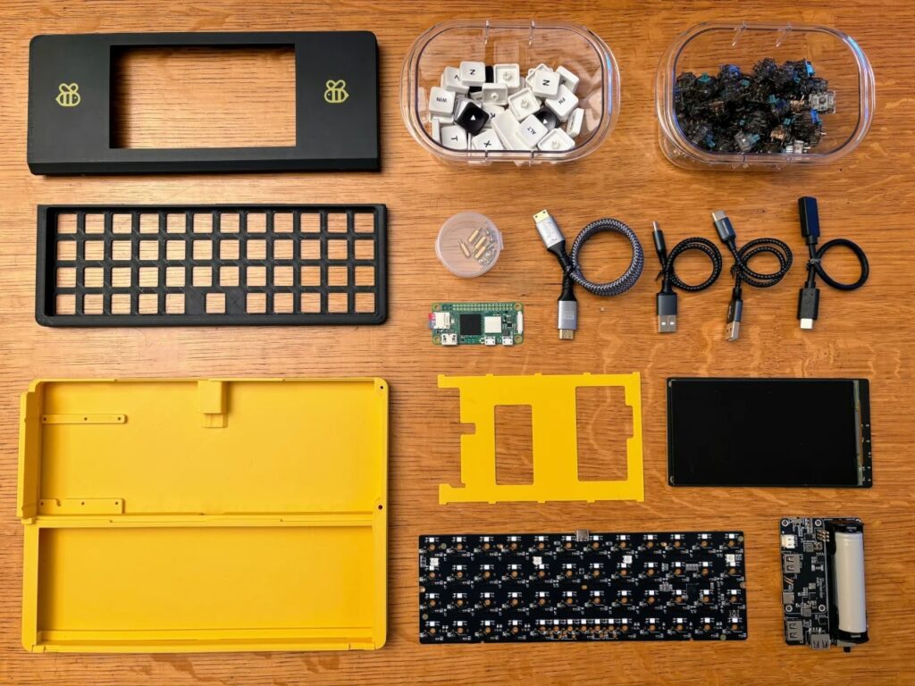 Overhead view of all disassembled hardware components of the Bee Write Back including Raspberry Pi Zero, battery, and keycaps.