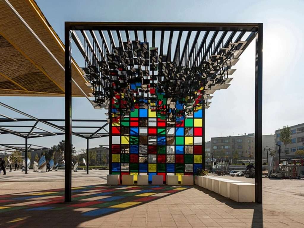 Symmetrical view of the Mirror Pavilion interior with vibrant colored shadows on the ground cast by a stained glass wall.