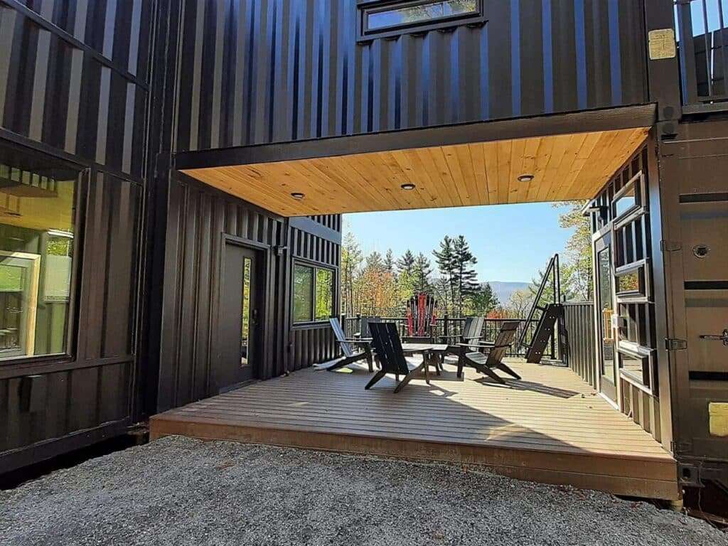 Covered outdoor wooden deck area under a cantilevered container at Fairmont Villa with outdoor seating.
