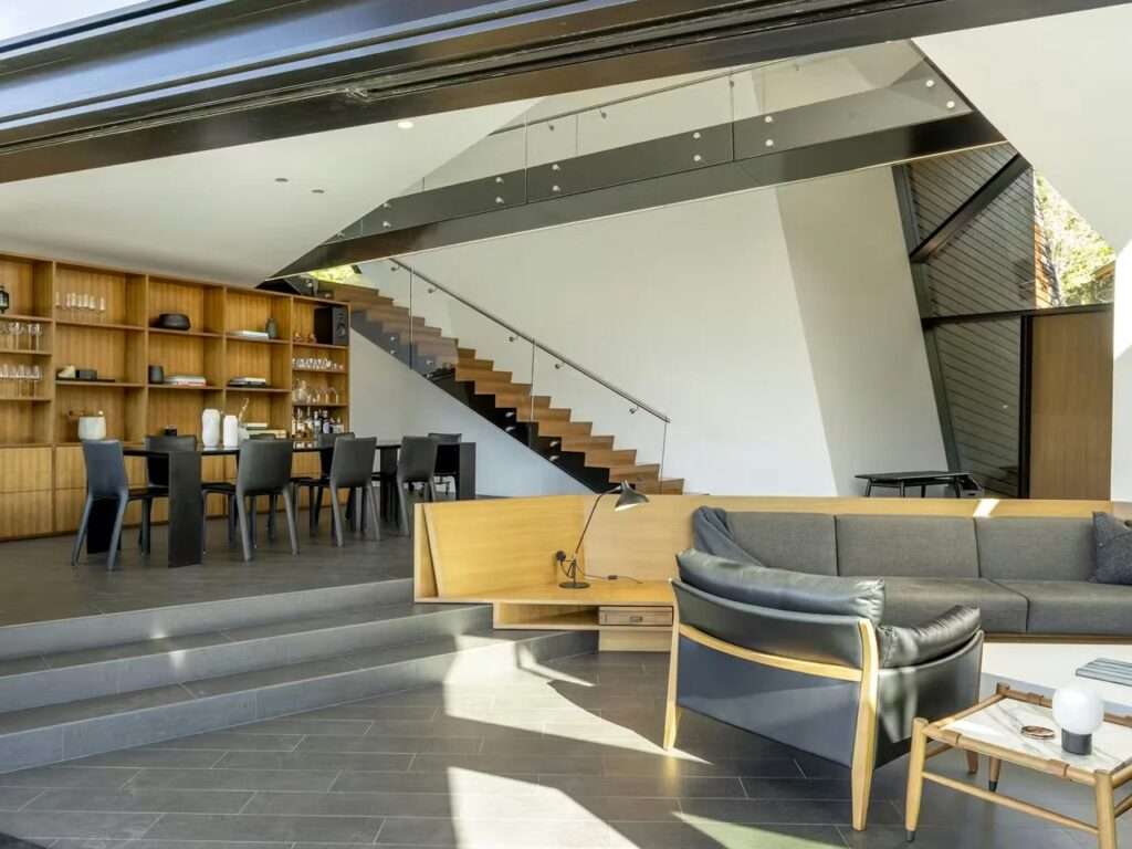 Open-plan interior of Hadaway House showing the wooden staircase with glass railings and a modern dining area.