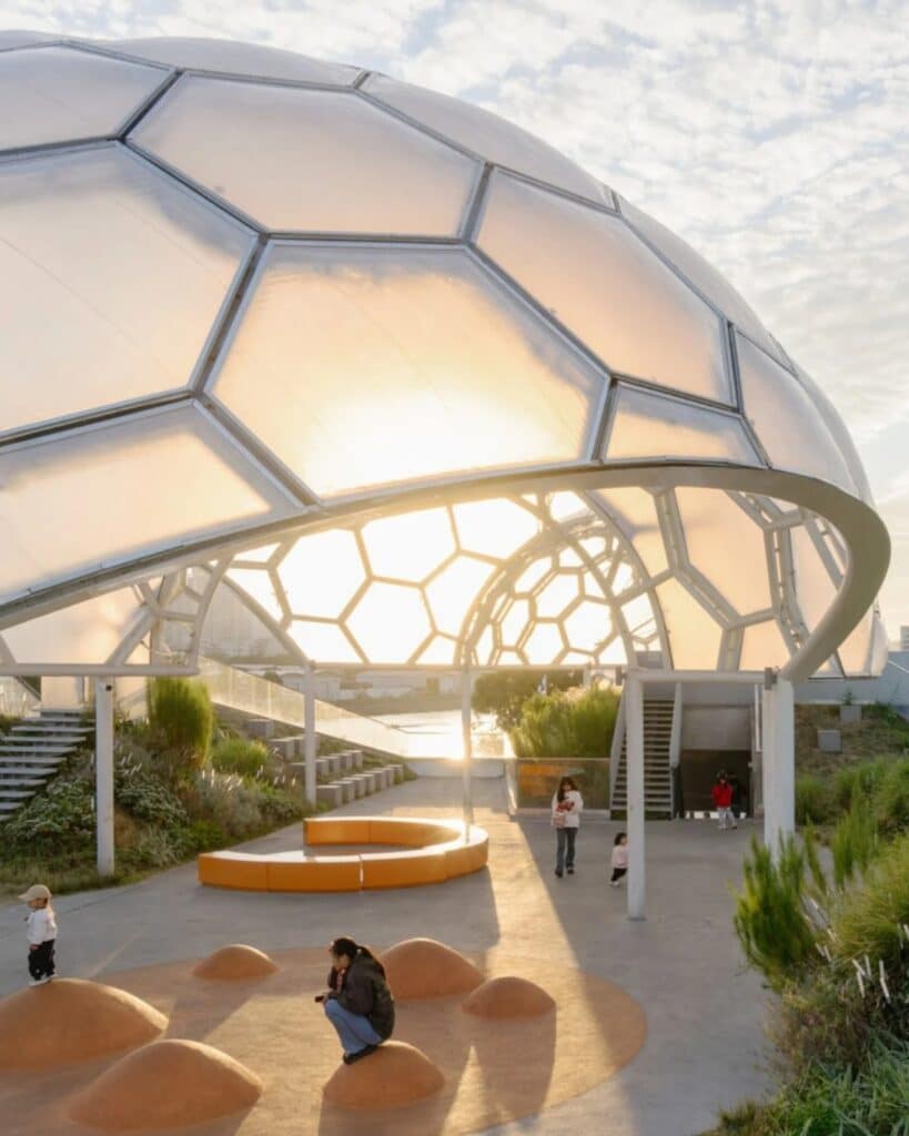 Interior view under the hexagonal dome at Yongping Warehouse rooftop park during sunset with people relaxing.
