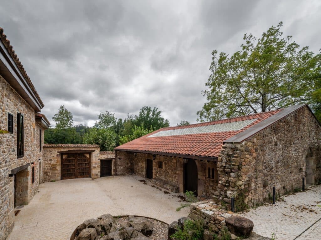 Exterior courtyard view showing the continuous surface of ceramic and glass tiles on the pavilion roof under a cloudy sky.