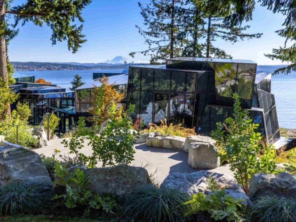 Elevated view of F-House glass volumes nestled in a rocky landscape with Mount Rainier in the distance.