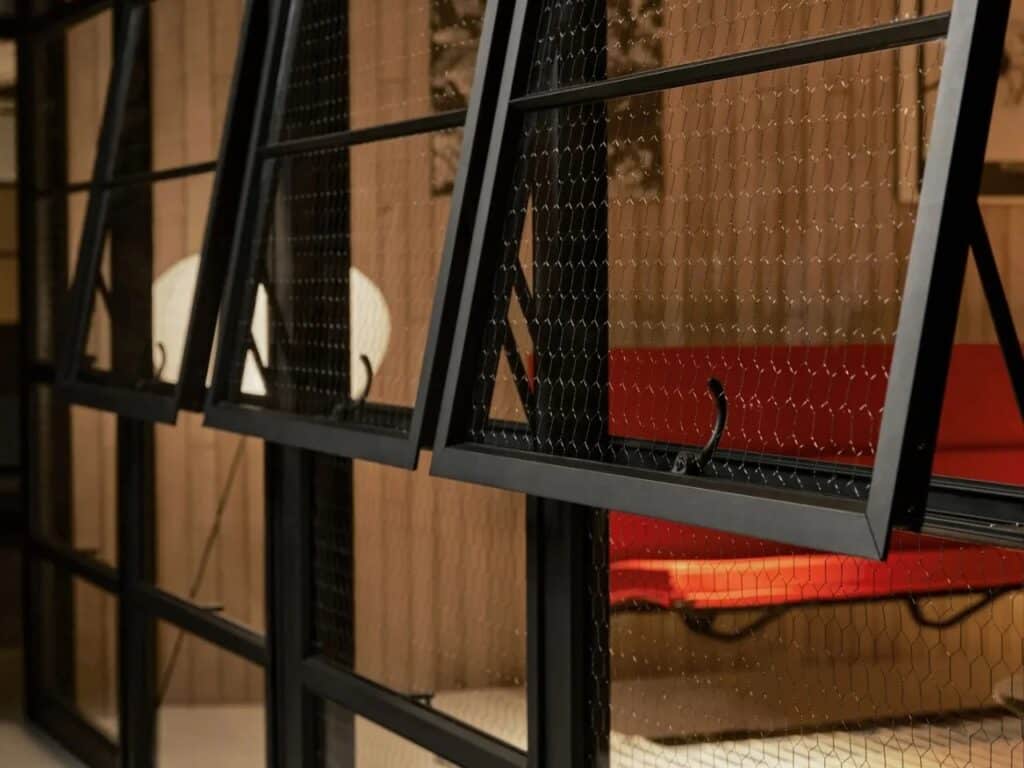 Close-up of black framed windows with chicken wire glass in the Eames Pavilion System.