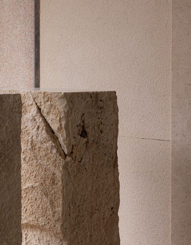 Close-up of a raw travertine stone block with natural textures and cracks used as a display plinth.