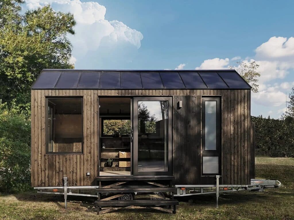 Frontal view of the Shoji House mobile home with sliding glass doors and dark wooden finish.