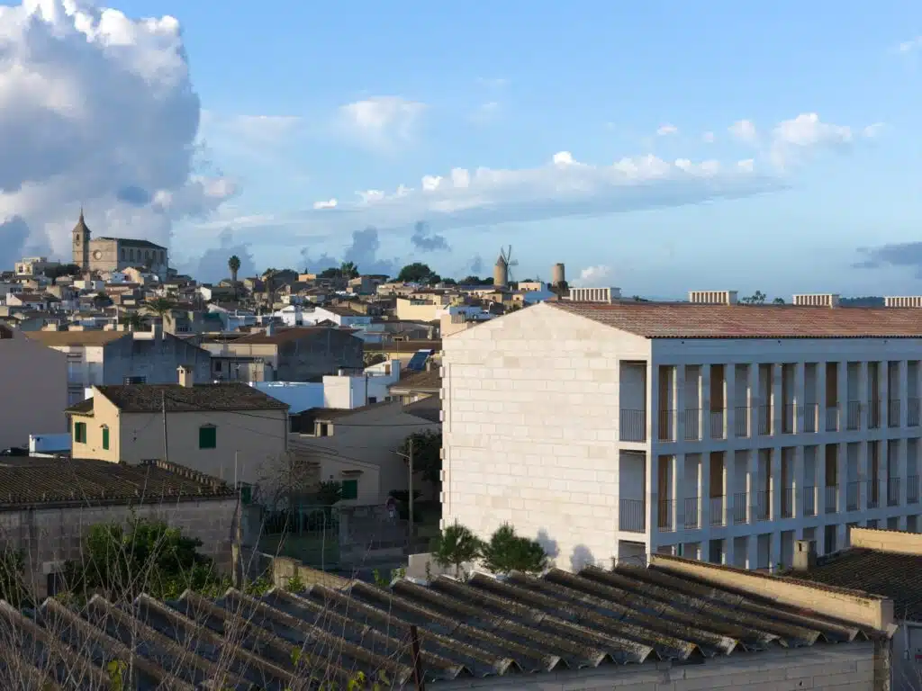 Aerial perspective of the Santa Margalida social housing project integrated into the historic town skyline with the local church in the background.