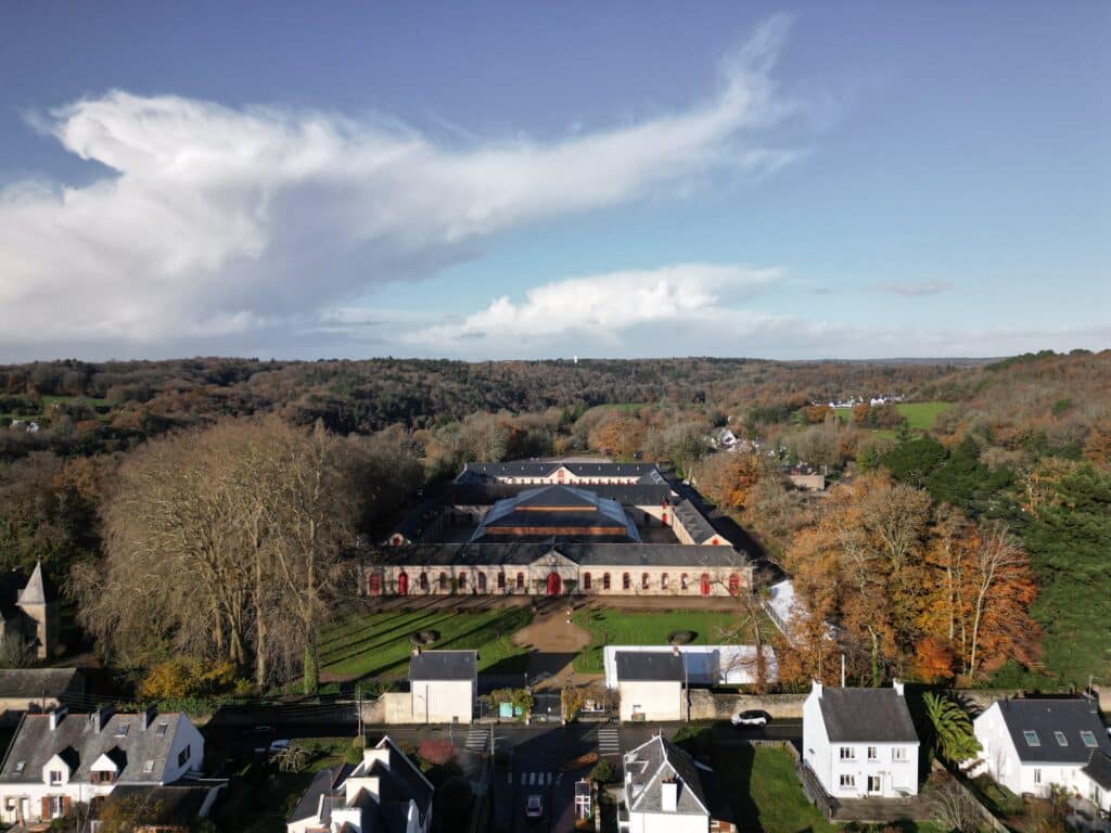 Aerial drone shot of the Hennebont National Stud Farm showing the new performance hall centered within the historic U-shaped courtyard.