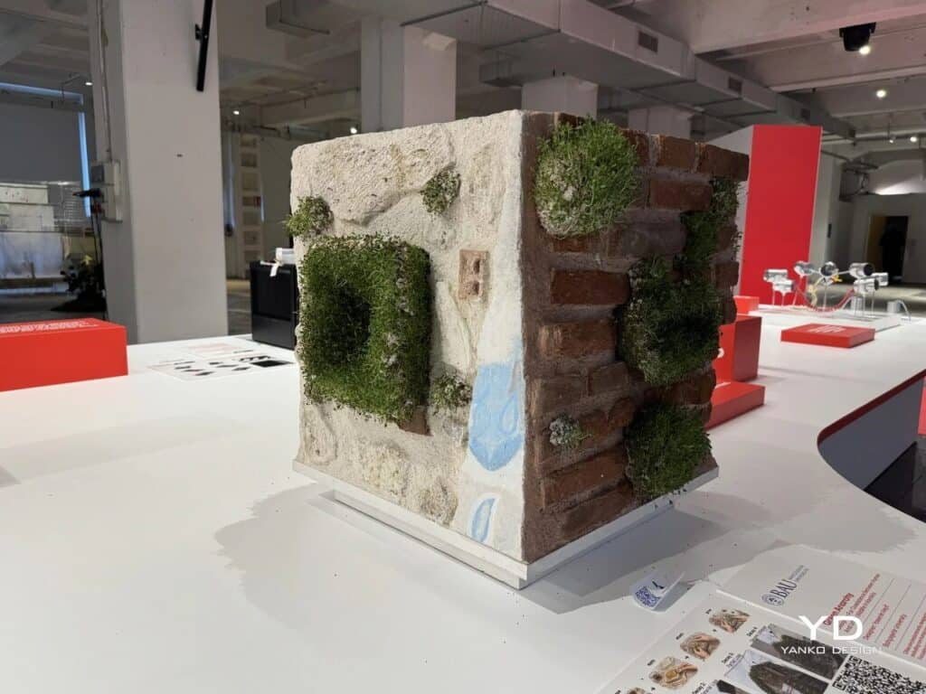 Architectural model of a wall corner with integrated green bio-units at an exhibition.