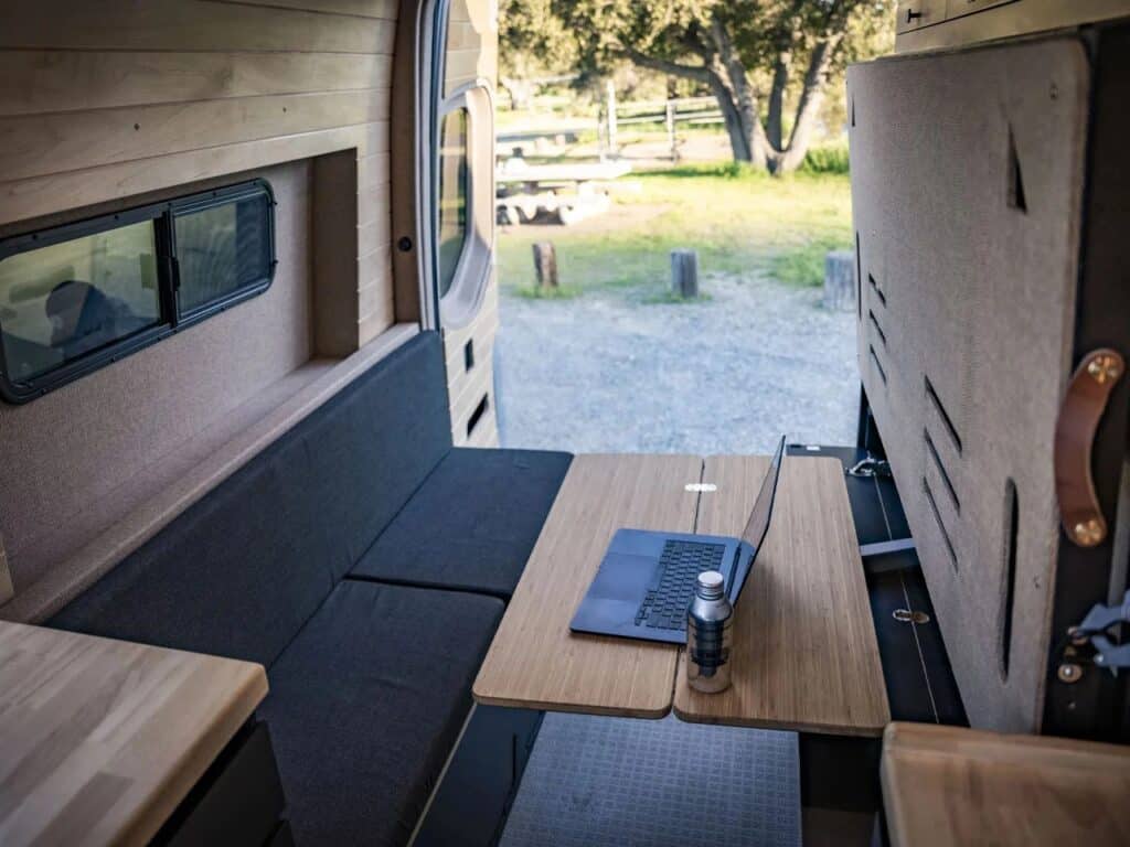 Interior shot of the living area featuring a laptop on a rotating bamboo table and a black upholstered bench.